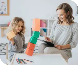 young girl engaging in a play activity with an adult woman using blocks